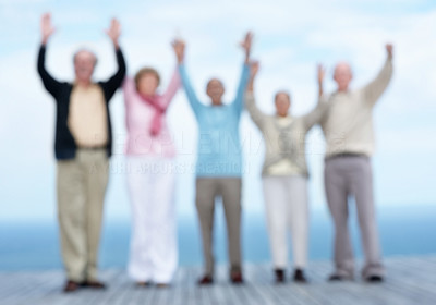 Group of senior friends with hand raised against the sky