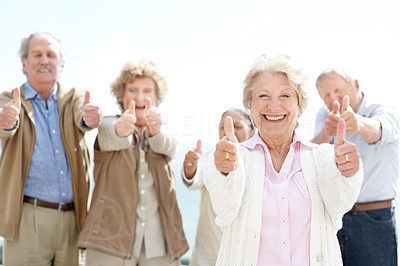Lovely old woman showing thumbs up sign with her friends