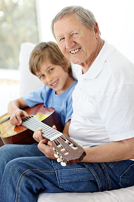 Happy little boy and grandfather playing guitar together