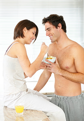 Cute young couple eating fruit salad in the kitchen