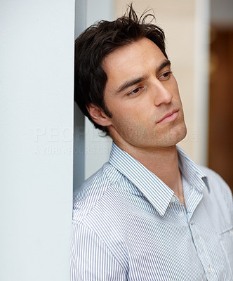 Young man leaning against a wall and thinking