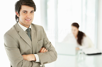 Young business man with hands folded and a colleague at the back