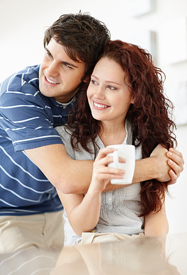 Happy daydreaming couple hugging eachother and drinking coffee