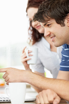 Young guy using a laptop with a woman drinking coffee
