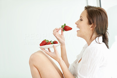 Happy young lady eating a plate of strawberries