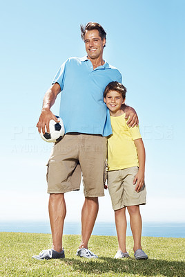 Happy father and son with a football standing outdoors