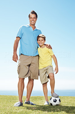 Cute little boy and his father with a football standing outdoors