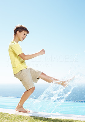 Happy little kid splashing water by leg at the pool