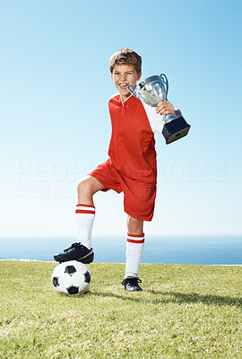 Excited small football player showing winners trophy