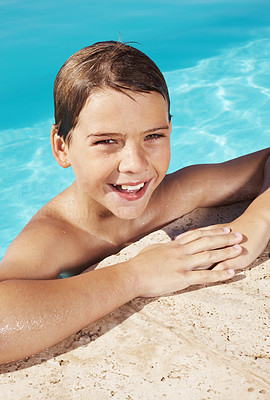 Happy little boy leaning on the side of a swimming pool
