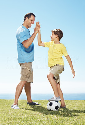 Man giving high five to his little son with a soccer ball