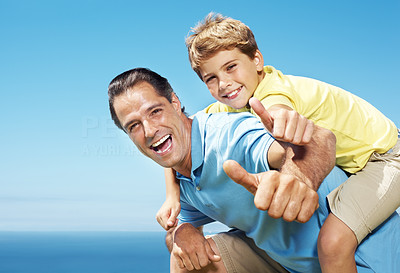 Man giving his son piggy back ride and showing thumbs up
