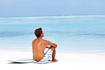 Young man sitting relax at the beach looking at ocean
