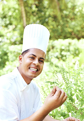 Happy young chef with basil leaves in garden