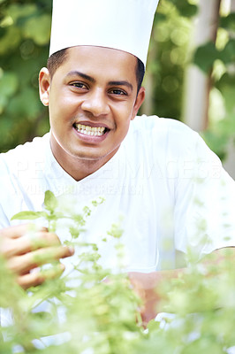 Smiling man wearing chef hat in herbs garden