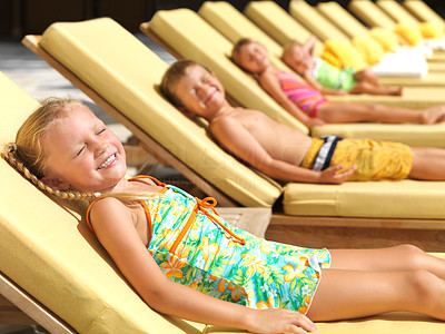 Cute little kids sunbathing by a pool