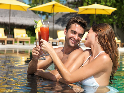 Attractive couple drinking cocktails in the pool
