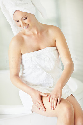 Young female wrapped in a bath towel sitting on the tub