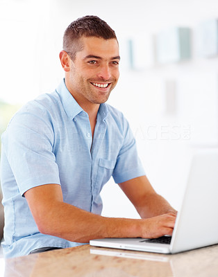 Young guy looking away while working on laptop
