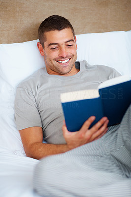 Happy young guy reading book at home