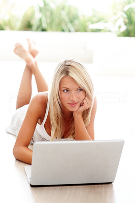 Young female lying on floor thinking while using laptop