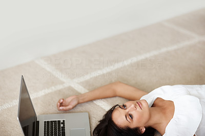 Cut image of a lovely woman lying on the floor besides a laptop