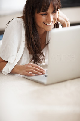 Happy female lying on the floor working on a laptop