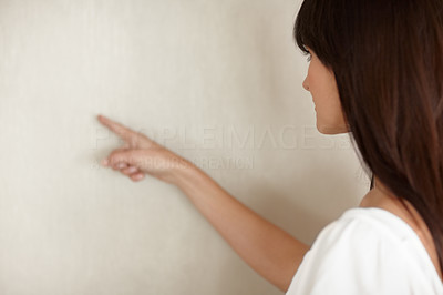 Young female pointing at the blank wall