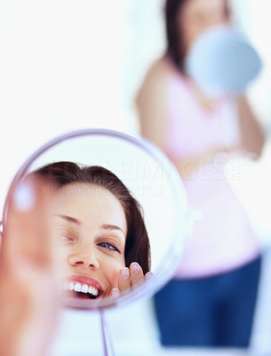 Female admiring her face into a hand mirror