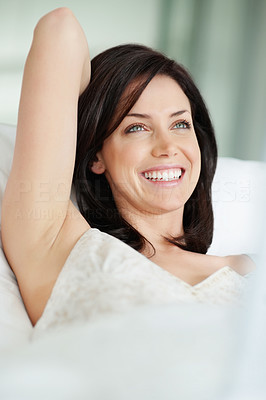 Happy woman in bed looking away in thought