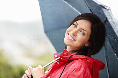 Smiling woman in red raincoat holding an umbrella