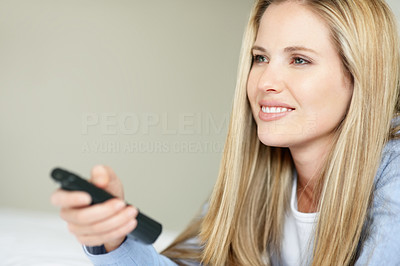 Beautiful young woman holding TV remote control