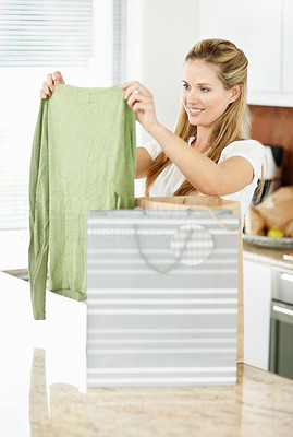 Woman with shopping bags at home , looking at new top