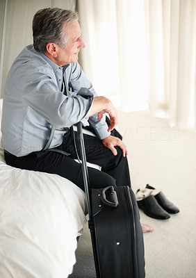 Thoughtful senior man sitting with support on travel bad