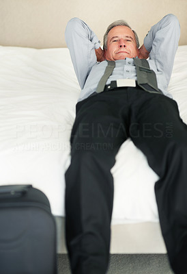 Relaxed senior business man lying in bed with hands behind head