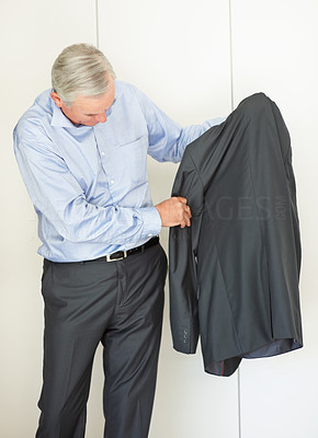 Senior business man looking at suit while getting ready to work