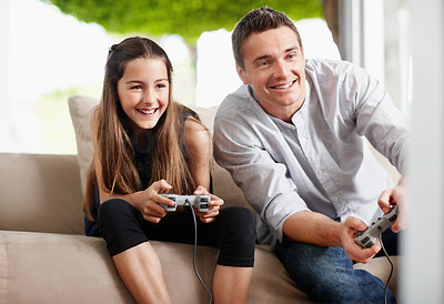 Daughter with father sitting in sofa while playing video game