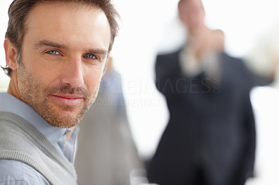 Middle aged man looking at you with people in blurred background