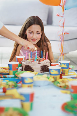 Person lighting candles on a birthday girl\'s cake