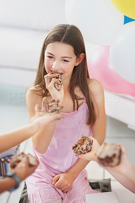Young girl eating birthday cake with friends offering her more