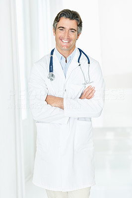 Successful male doctor standing in corridor with arms folded