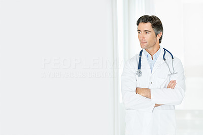 Mature male doctor with arms folded looking at copy space