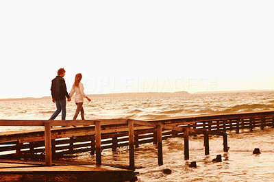 Couple holding hands and walking on a jetty
