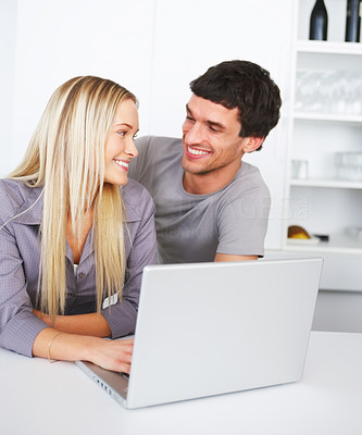Happy couple using a laptop in the kitchen