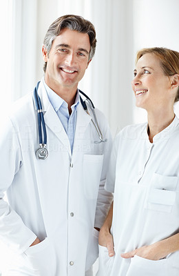 Mature doctor and nurse standing together and smiling