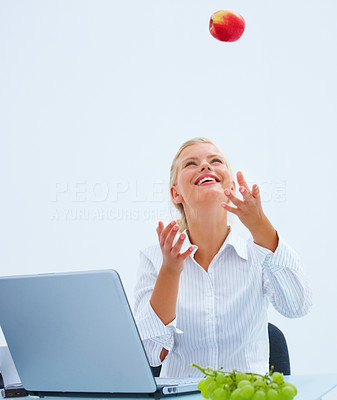 Pretty business woman playing with a apple by laptop at desk