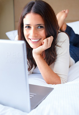 Closeup of a beautiful woman lying on bed and using laptop