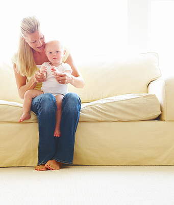 Mother with her baby boy sitting on sofa at home