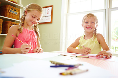 Smiling girls sitting by table and drawing