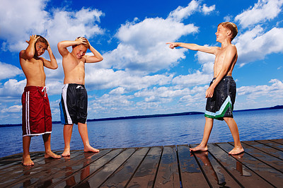 Small boy pointing finger at two friends standing on a wooden deck